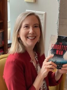 Author Lisa M. Lilly holding a copy of new release The Forgotten Man (A Q.C. Davis Mystery)